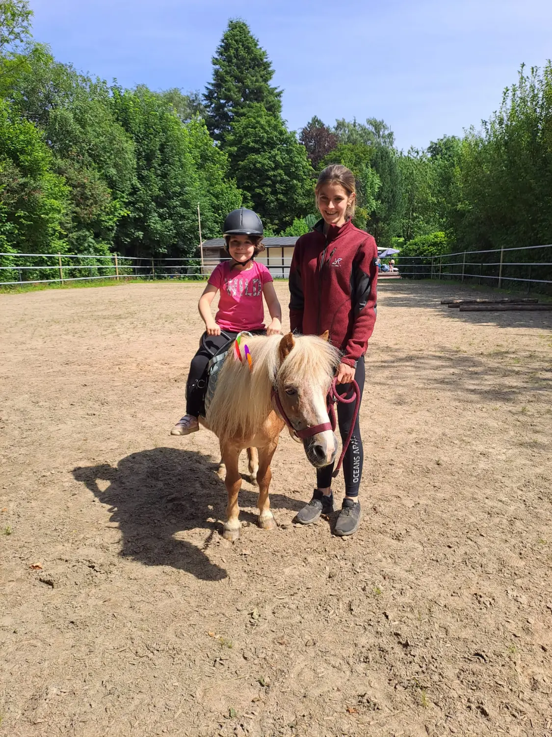 Pferderanch Sauerland – ein kleines Kind reitet auf einem Pony, ein anderes Kind steht daneben.