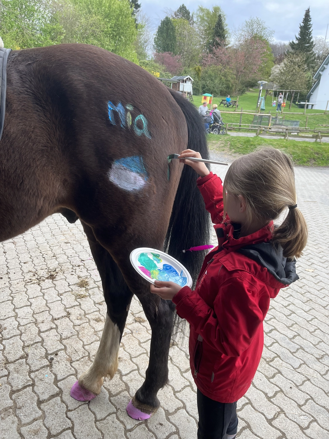 Pferderanch Sauerland – ein kleines Mädchen malt ein Pferd und schreibt einen Namen auf den Rücken des Pferdes.